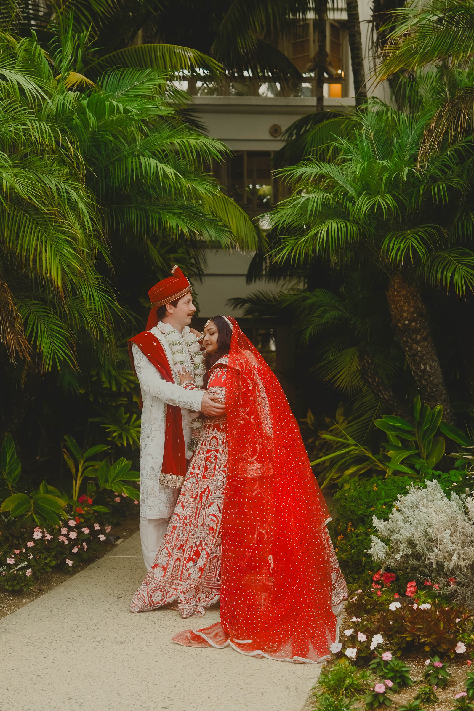 Lakshmi and Isaac in their wedding attire beneath palm leaves